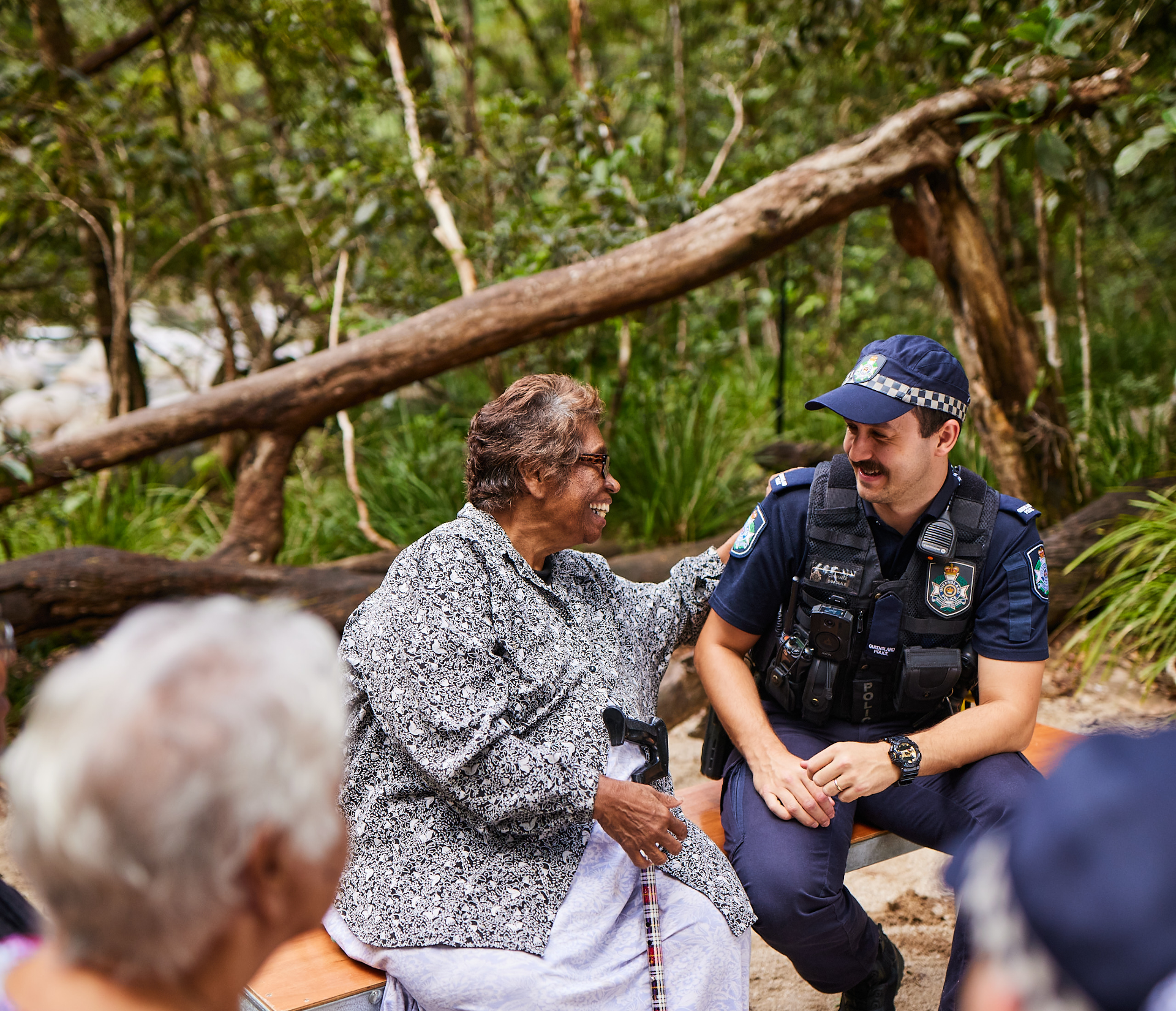 A group of people sat yarning with a police officer in a tropical rainforest setting