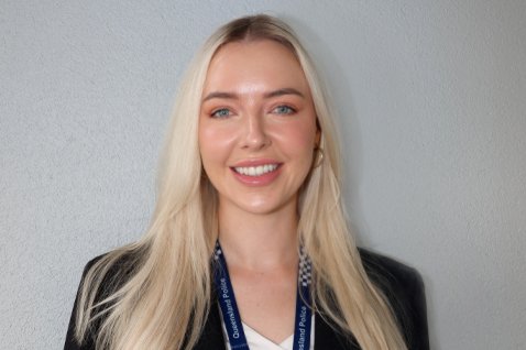 Photo of a person in front of a light grey wall.