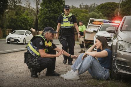 police officers talk to young woman after car crash
