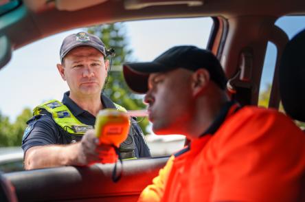 Police officer conducting breath test of driver