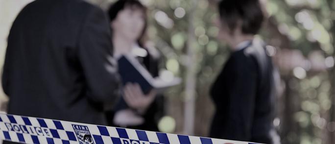 soft focus image of police talking to someone behind a crime scene tape