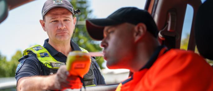 Police officer conducting breath test of driver
