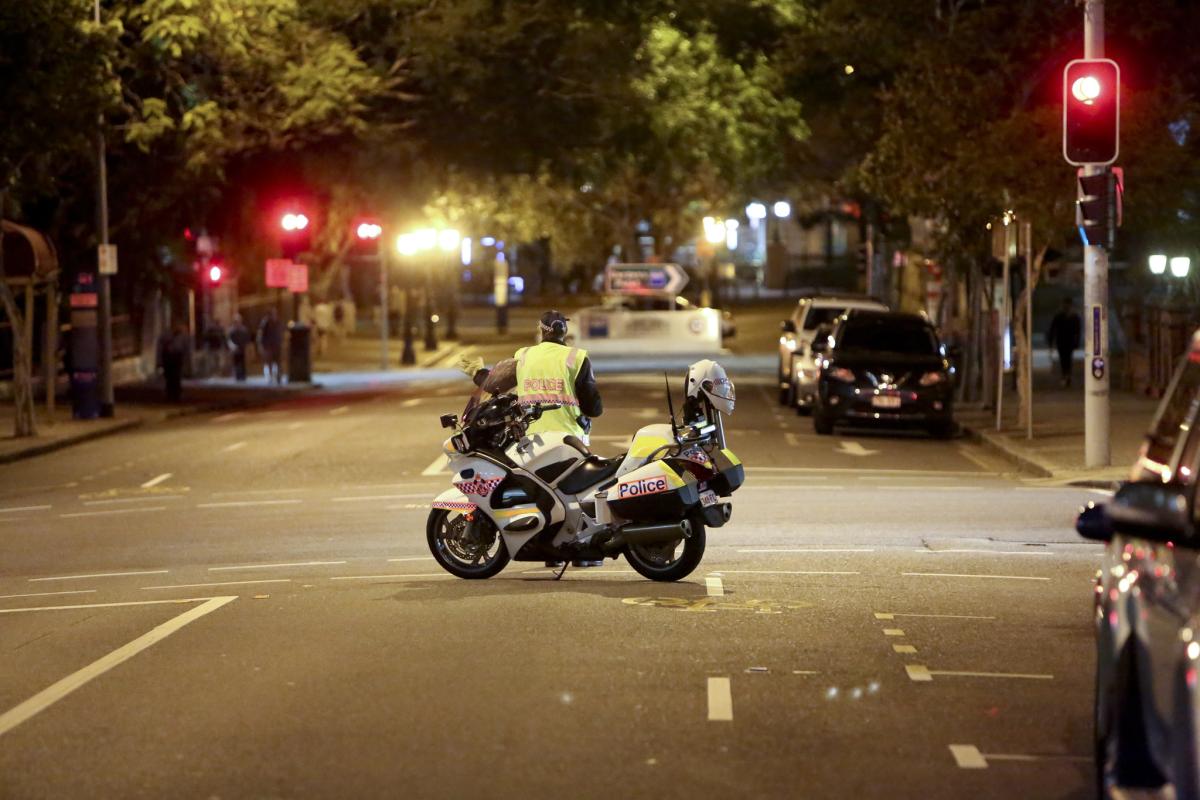 Police officer standing by a motorcycle on a street at night