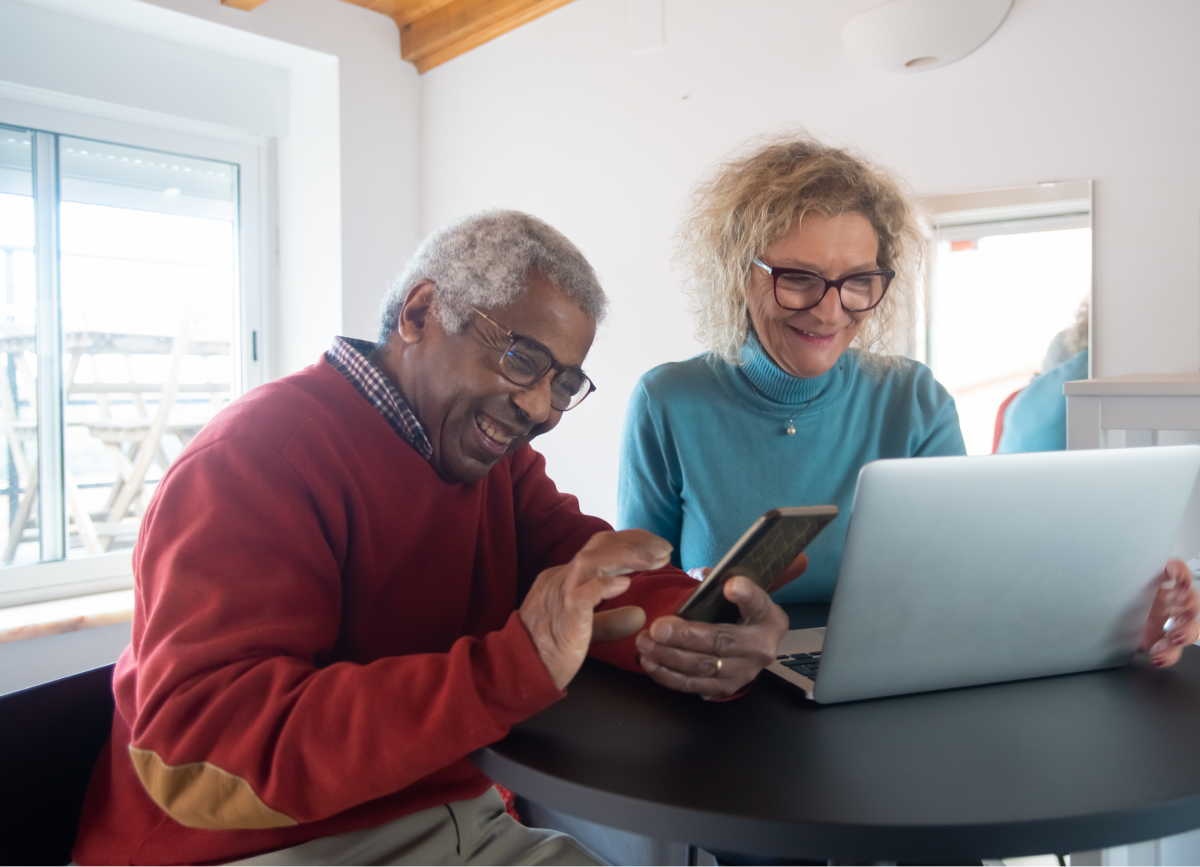 A man and a woman laugh looking at a laptop