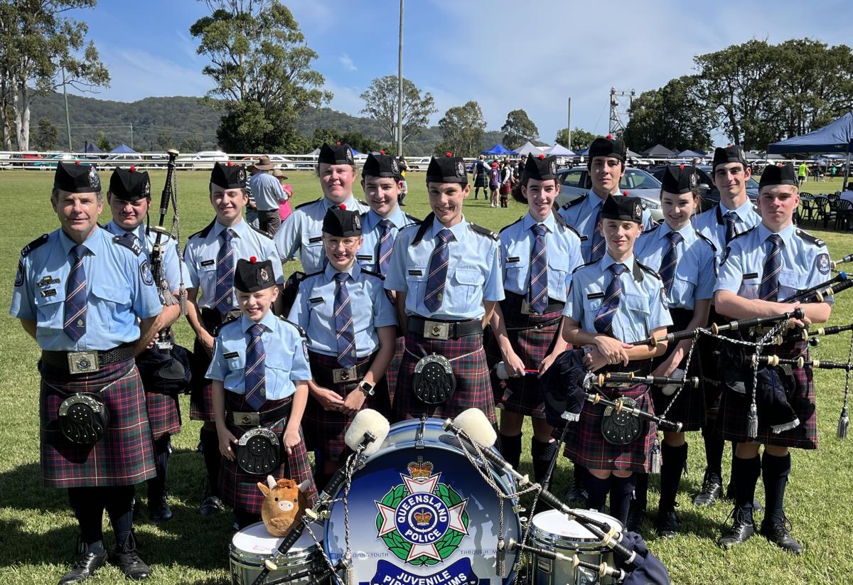 Queensland Police Juvenile Pipes and Drums band with tutors lined up behind their drums.