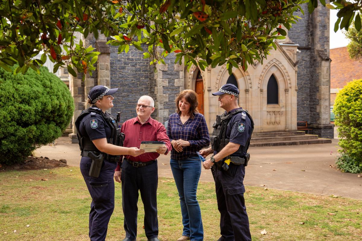 Police officers share information sheets with man and woman outside a church