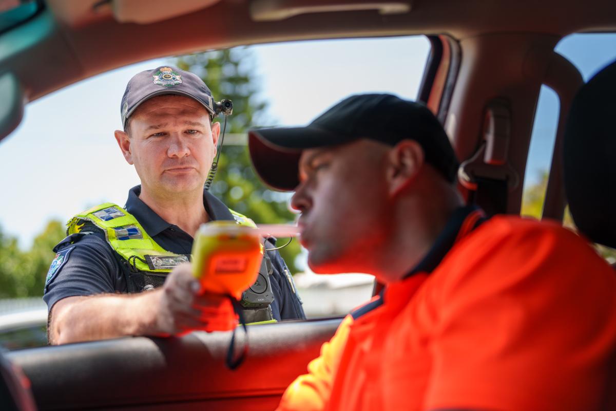 Police officer conducting breath test of driver