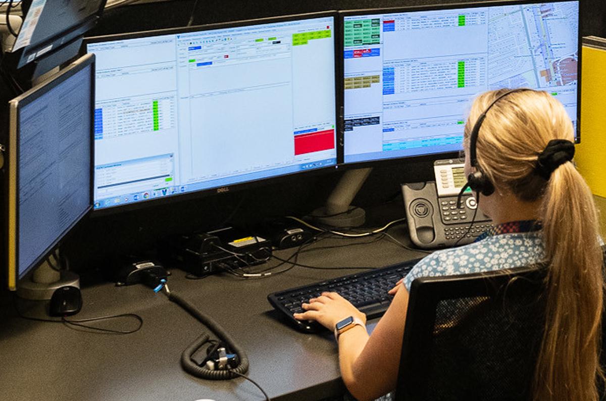 Policelink Customer Service Officer working in front of monitors wearing headphones
