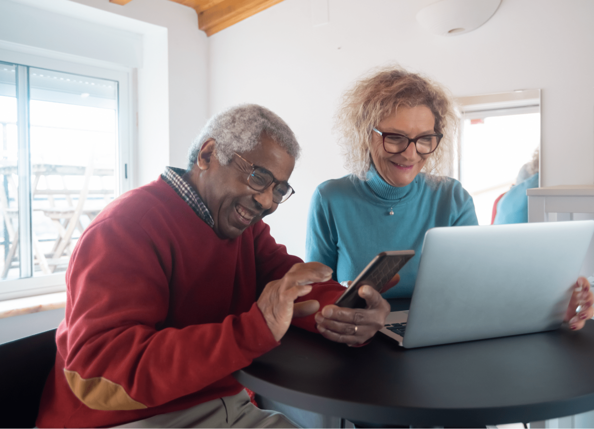 A man and a woman laugh looking at a laptop